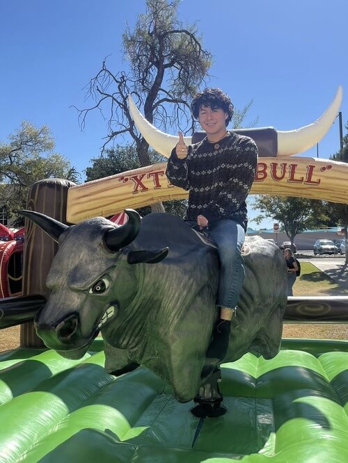 David on top of a mechanical bull giving a thumbs up to the camera